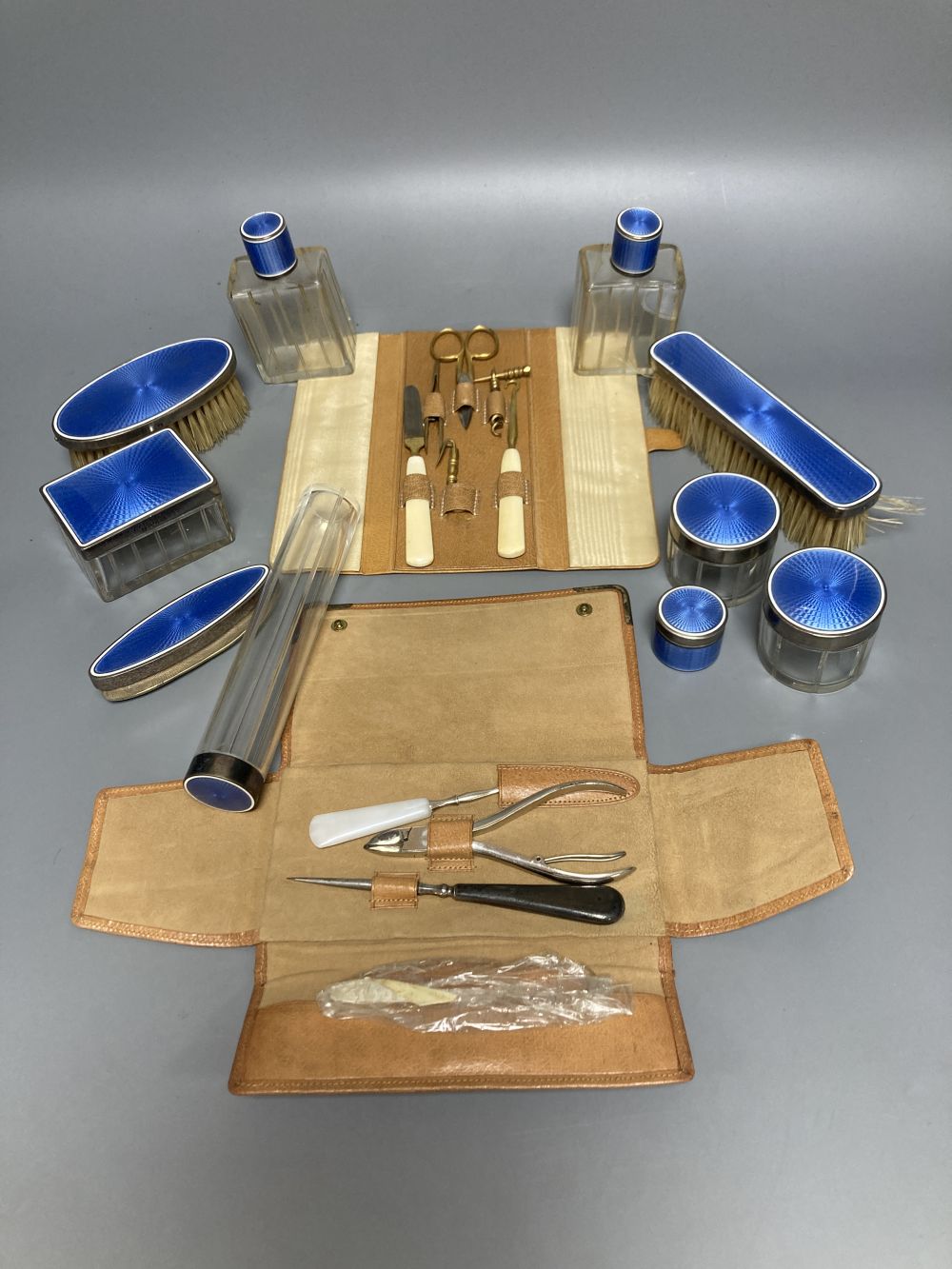 A late 19th/early 20th century French ten piece white metal and blue guilloche enamel travelling toilet set in leather case,